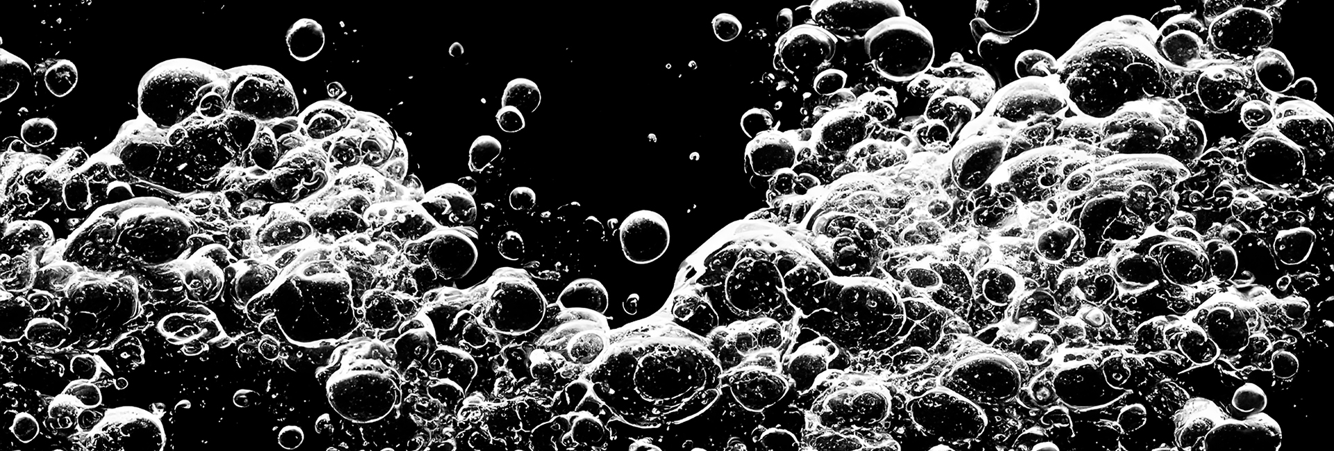 a black and white photo of bubbles in a liquid on a black background.