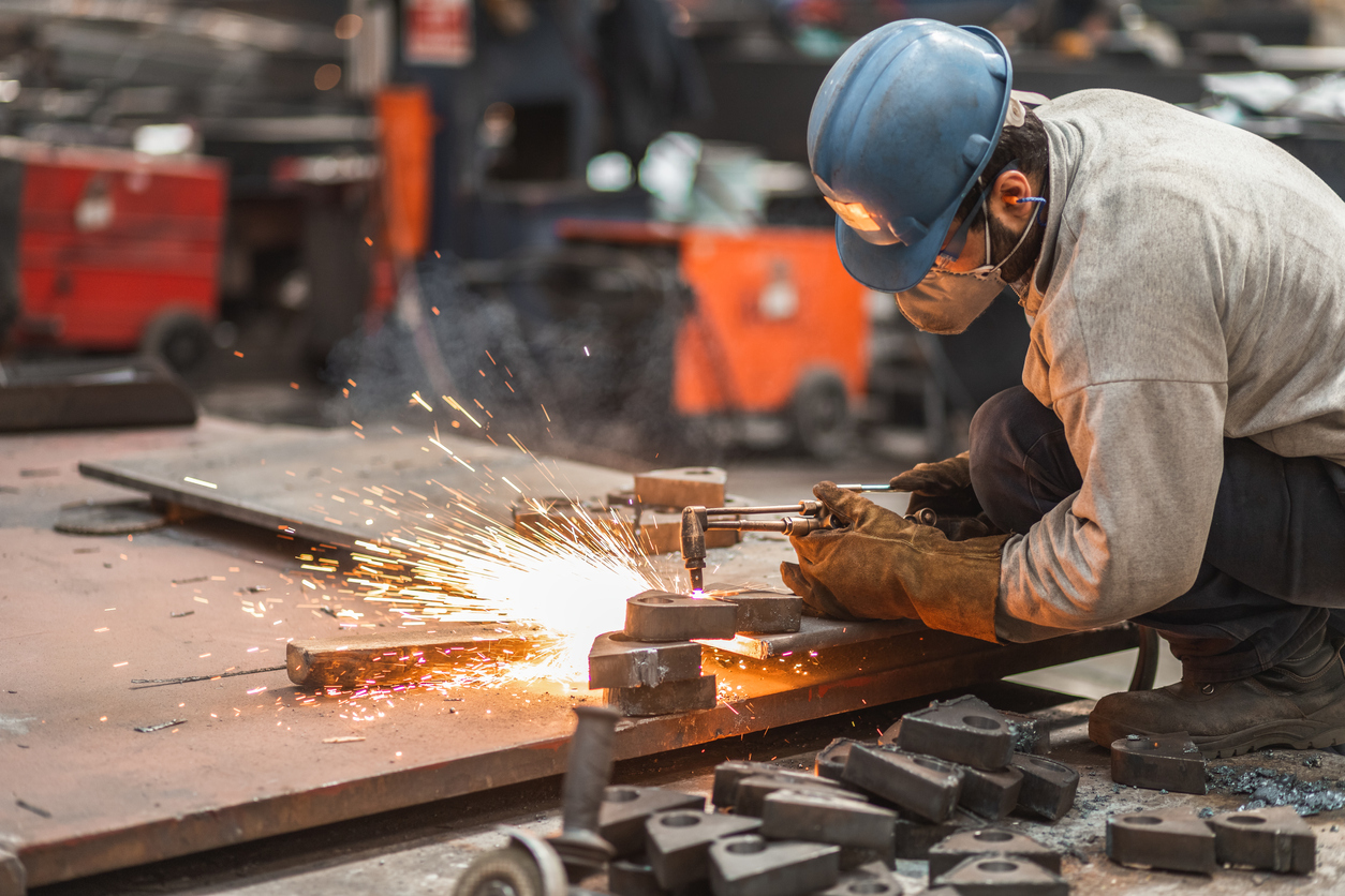 a man wearing a blue hard hat is cutting metal