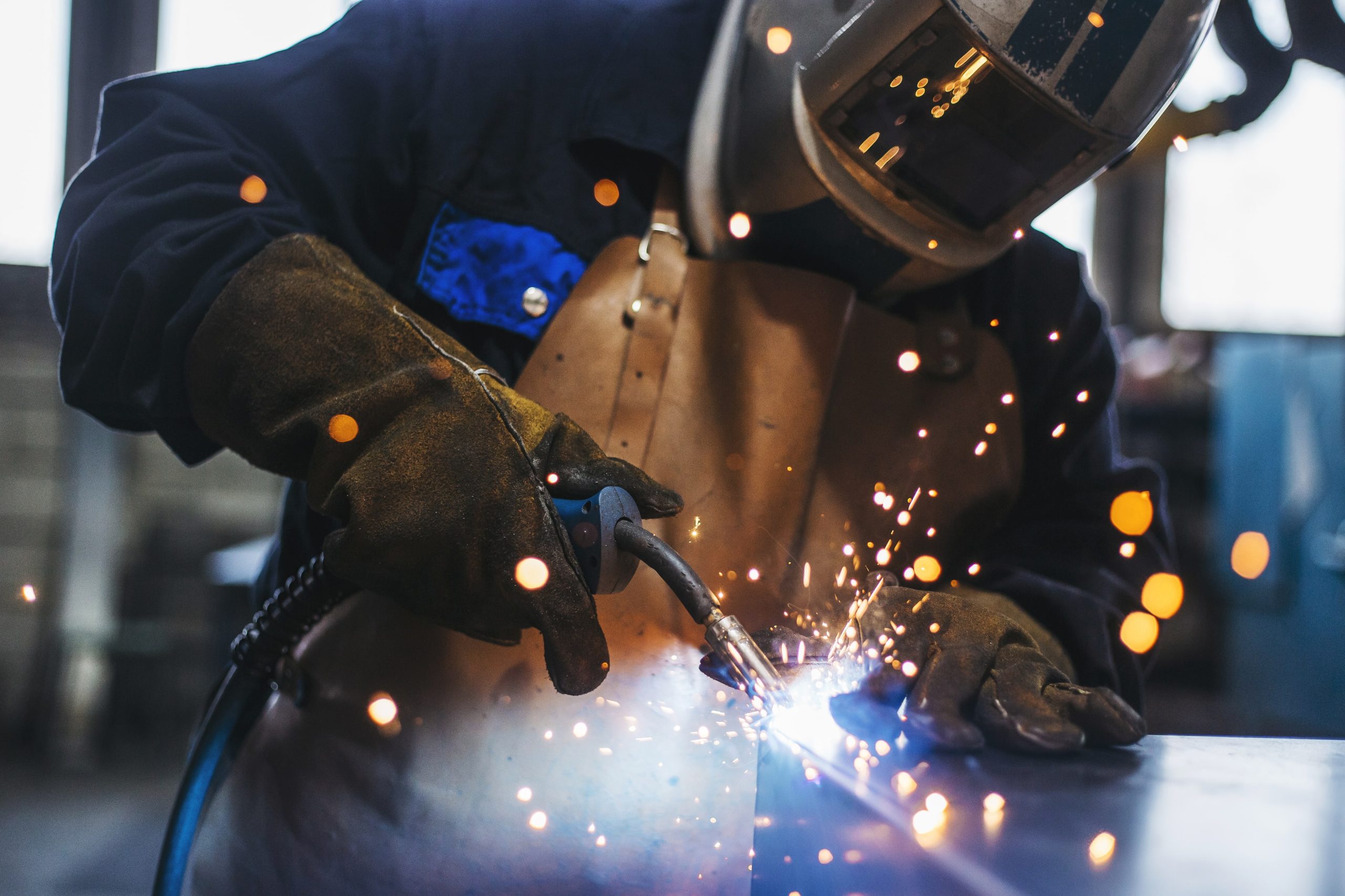 a man wearing a welding helmet is welding a piece of metal