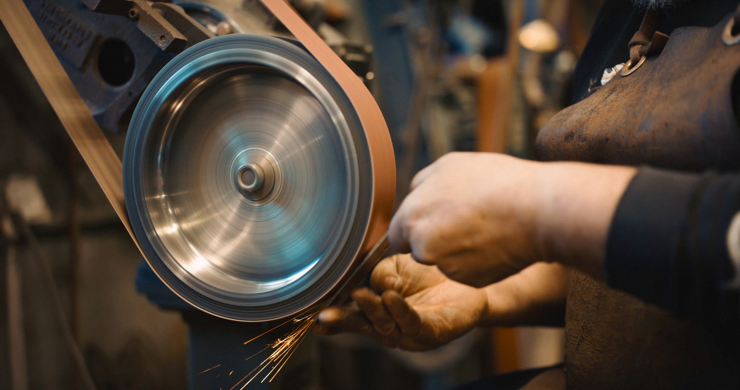 a person grinding a piece of metal with a belt that says ' stainless steel ' on it